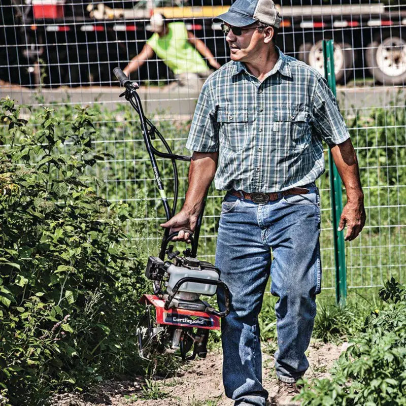 man lifting the Earthquake 31452  33cc  MAC 2-cycle  Cultivator on his right hand