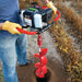 man  drilling hole on the ground using Earthquake 43cc Earth Auger Powerhead