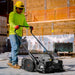 Man Sweeping the Construction Site Floor Using the 30" Battery Powered Push Sweeper with Triple Power Brooms Electric Drive and Dust Suppression