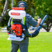 Man Carrying the Tomahawk 4 Gallon Motorized Backpack Spreader with 79cc Engine for Fertilizer, Pesticide, Rock Salt