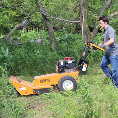 Side view of a man pushing the Brave Pro 26 Inch Walk Behind Brush Cutter (BRPBC26HE) Powered by Honda GX390 Engine