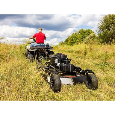 Rear view of a man driving his ATV  with the swisher RC14544CP4K in a high dense sward