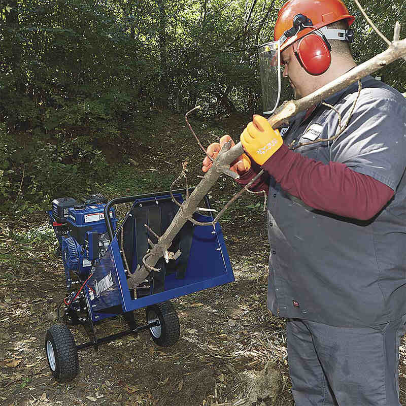 man holding a branch on his both hands while feeding it to the Powerhorse Rotor Wood Chipper 