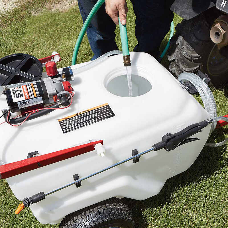 man filling water on the NorthStar Tow-Behind Broadcast and and spot Sprayer-31 gallon