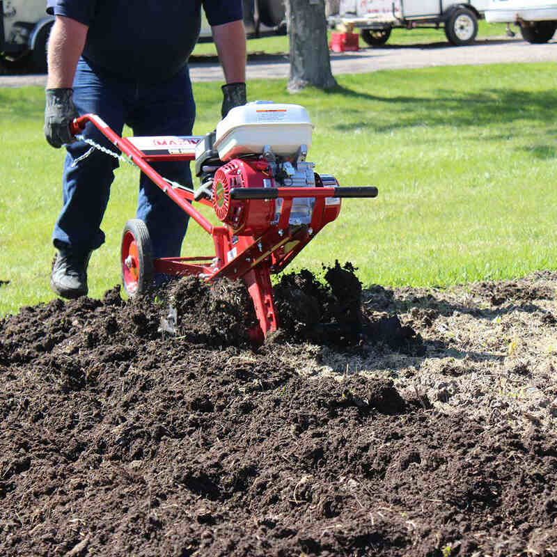 man operating his maxim commercial tiller on the flied and tiller's blade is covered with mud