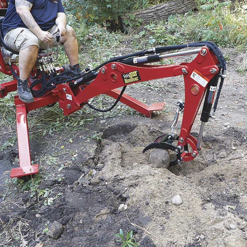 man operating his Nortrac towable trench while trying to grab the rock