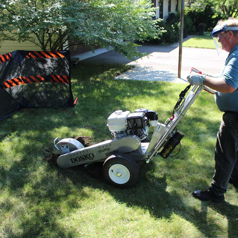 man with face shield grinding the tree stump using the Dosko Stump grinder