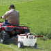 man riding his ATV with the NorthStar tow-behind broadcast and spot sprayer-21 gallon capacity mounted on it