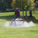 man spraying his lawn while riding his lawn mower with NorthStar tow-Behind broadcast and spot sprayer mounted on it