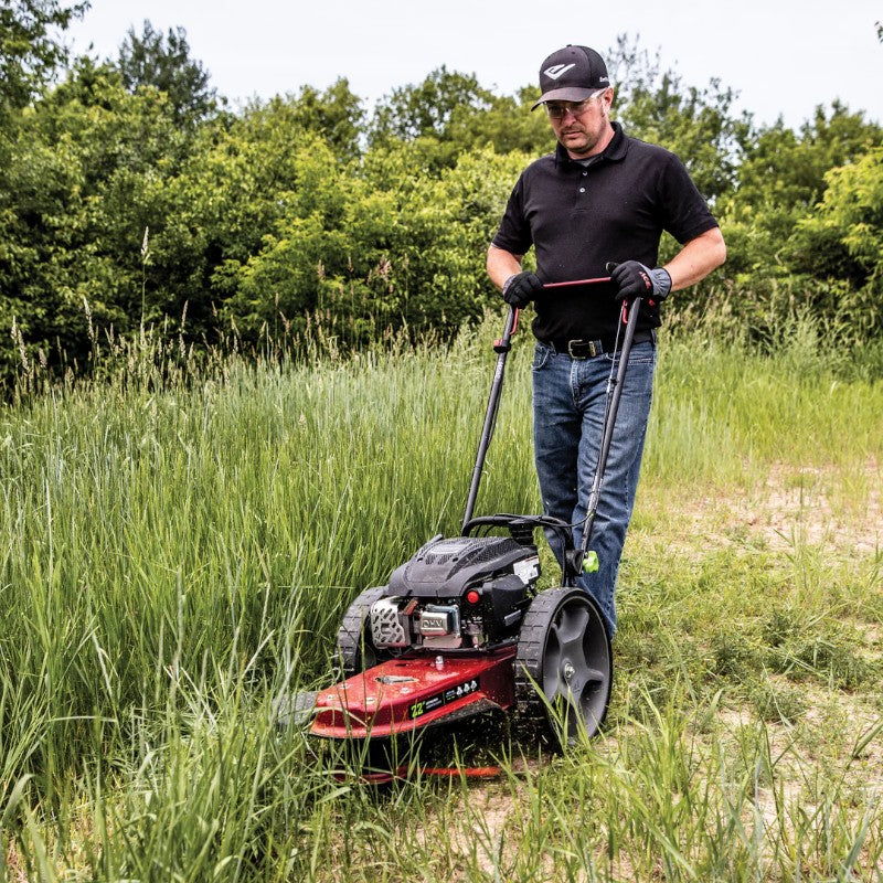 man using The Earthquake Walk Behind String Mower powered by a 160cc 4 Cycle Viper engine to clear a tall grass field