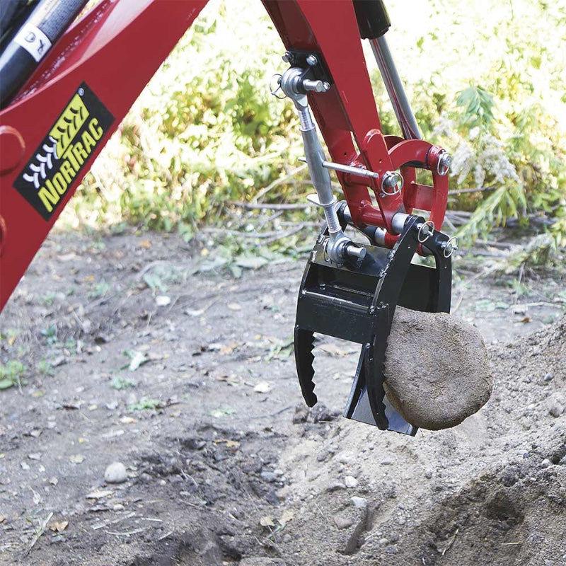 Nortrac rock grabber arm installed on the Nortrac towable trencher picking up a heavy rock