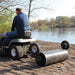 rear view of a man riding his lawn mower with maxim lawn roller installed on it hitch