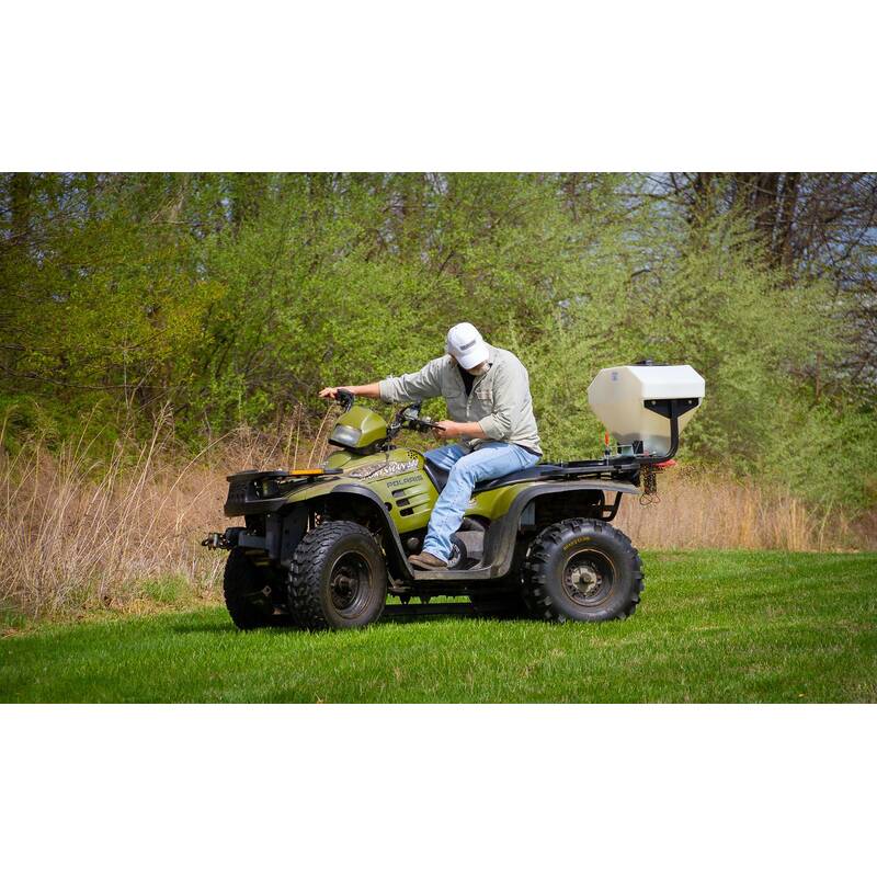 man driving an ATV with swisher ATV spreader