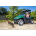 side view of a man driving a green UTV while plowing the dirt