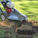 closed up image of a dosko walk behind stump grinder grinding the tree stump with a lot of small debris  splashing from its cuttter blade